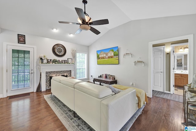 living room featuring dark wood-style flooring, a fireplace, ceiling fan, vaulted ceiling, and baseboards