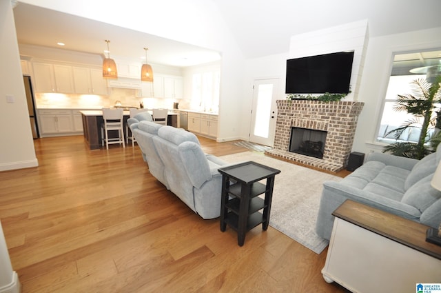 living area featuring recessed lighting, a fireplace, light wood finished floors, baseboards, and lofted ceiling
