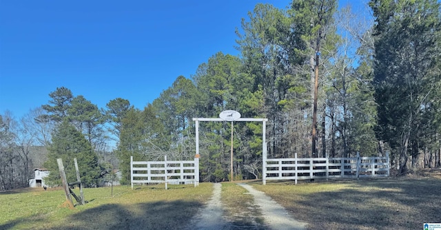 view of gate with fence and a yard
