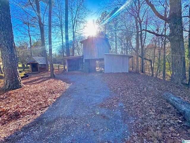 exterior space featuring a chimney, aphalt driveway, and an outbuilding