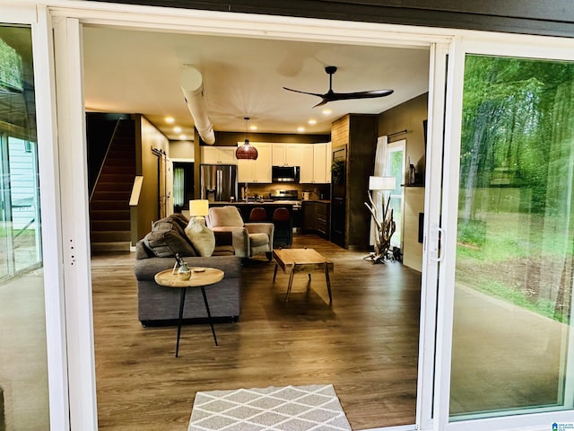 living room featuring wood finished floors, a ceiling fan, recessed lighting, and stairs