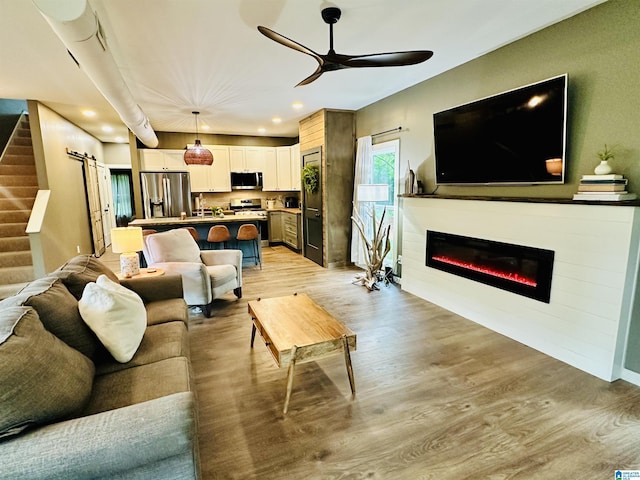 living area featuring light wood finished floors, a ceiling fan, stairway, and recessed lighting