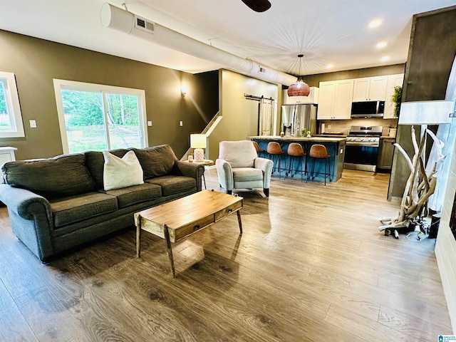 living room featuring light wood finished floors, recessed lighting, and visible vents
