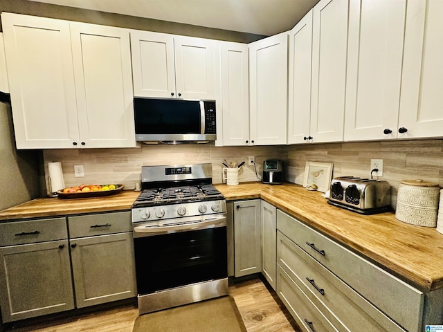 kitchen featuring tasteful backsplash, appliances with stainless steel finishes, butcher block countertops, light wood finished floors, and gray cabinets