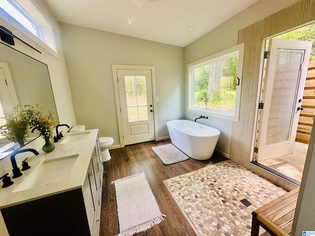 bathroom featuring toilet, a sink, wood finished floors, and a soaking tub