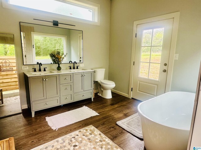 bathroom with double vanity, a sink, a freestanding tub, and wood finished floors