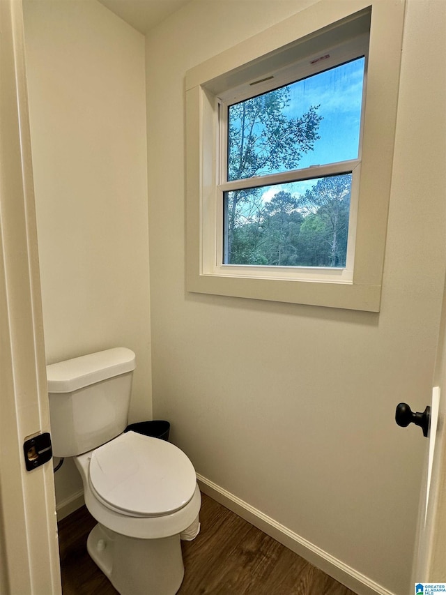 bathroom with baseboards, wood finished floors, and toilet