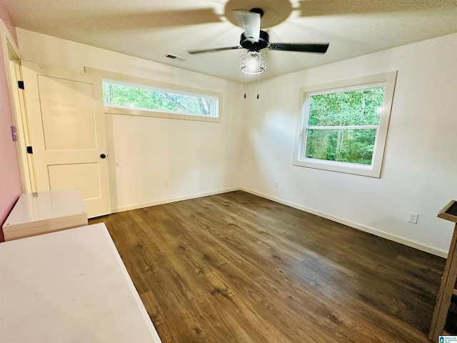 spare room with baseboards, visible vents, ceiling fan, and dark wood-type flooring