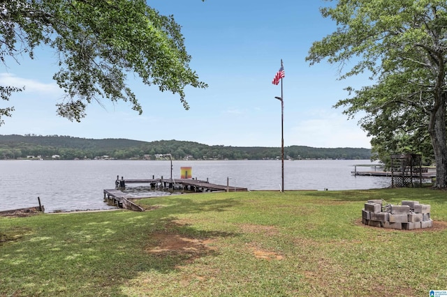 view of dock with a lawn and a water view