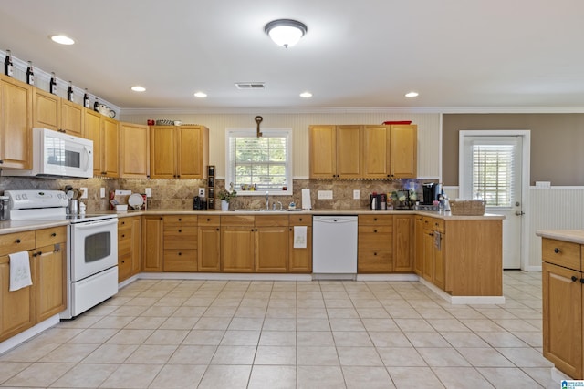 kitchen with visible vents, ornamental molding, a peninsula, white appliances, and a sink
