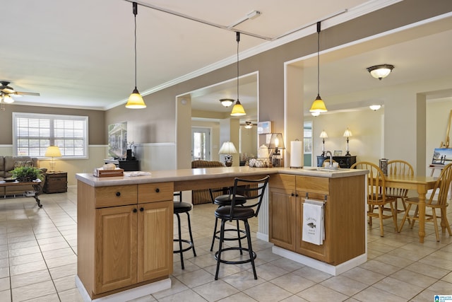 kitchen with a ceiling fan, a kitchen bar, light tile patterned floors, light countertops, and open floor plan