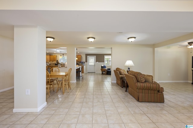 living room featuring light tile patterned floors, baseboards, and a ceiling fan