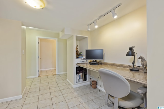 office space featuring baseboards, built in desk, rail lighting, and light tile patterned flooring