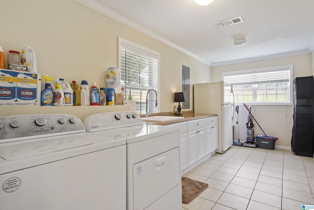 washroom with crown molding, washer and clothes dryer, a sink, cabinet space, and light tile patterned floors