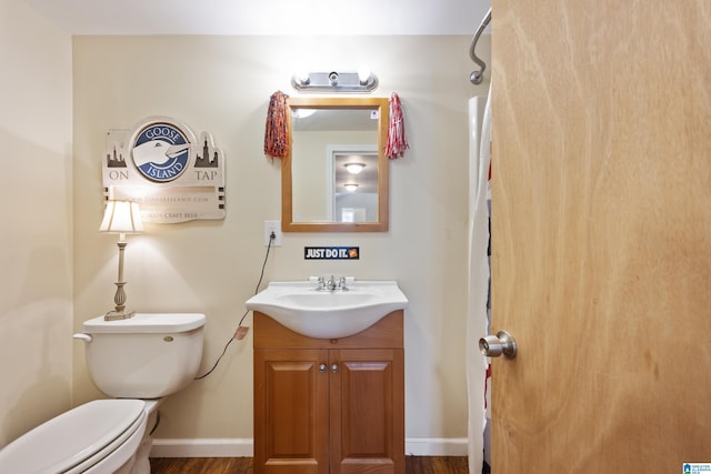 bathroom with vanity, baseboards, wood finished floors, and toilet