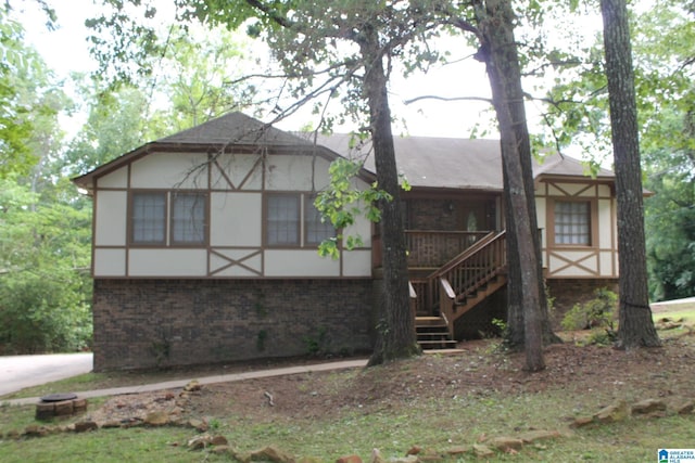 back of property featuring brick siding, stucco siding, and stairs