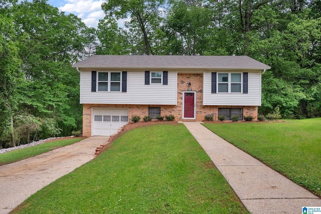 raised ranch with concrete driveway, a front lawn, an attached garage, and brick siding