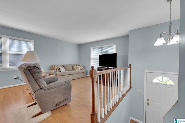 living area with an inviting chandelier, light wood finished floors, and plenty of natural light