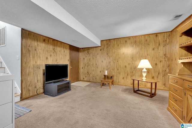 unfurnished room with wood walls, a textured ceiling, and light colored carpet