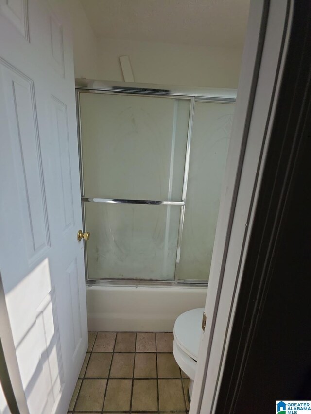 bathroom featuring tile patterned floors, toilet, and shower / bath combination with glass door