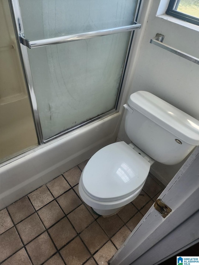 bathroom featuring shower / bath combination with glass door, toilet, and tile patterned flooring