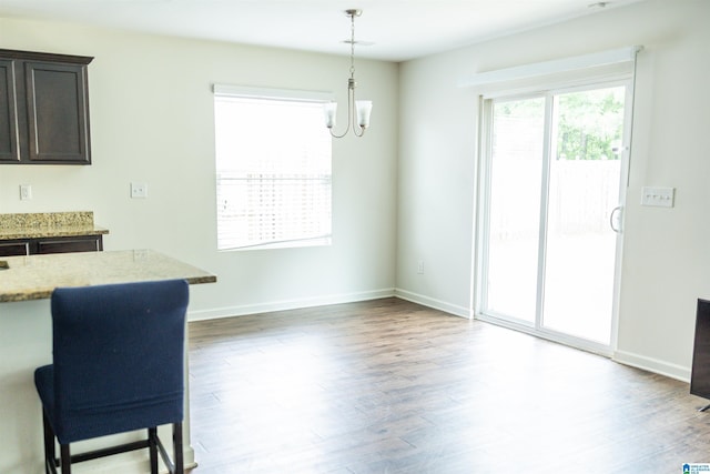 unfurnished dining area featuring a chandelier, wood finished floors, and baseboards