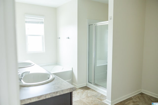bathroom featuring a shower stall, baseboards, double vanity, and tile patterned flooring