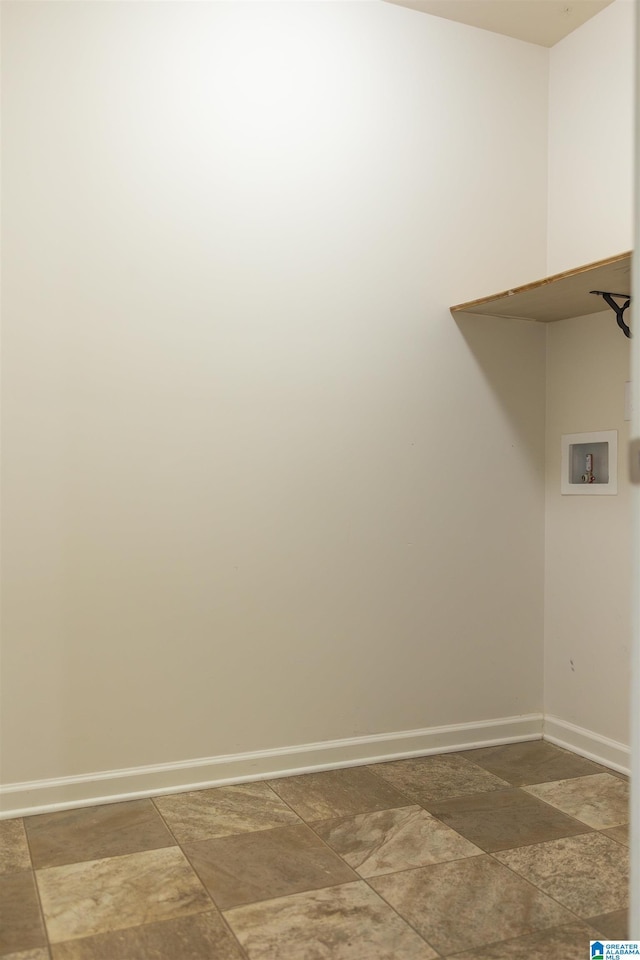 washroom with hookup for a washing machine, light stone finish flooring, and baseboards