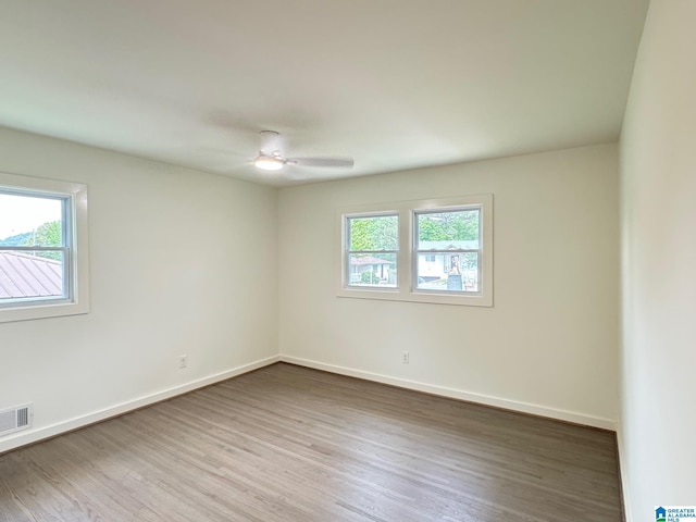 unfurnished room featuring baseboards, visible vents, and wood finished floors