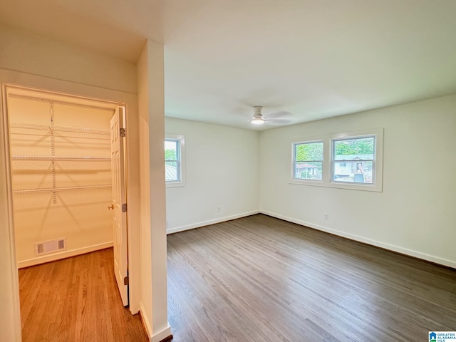 empty room with a ceiling fan, baseboards, visible vents, and wood finished floors
