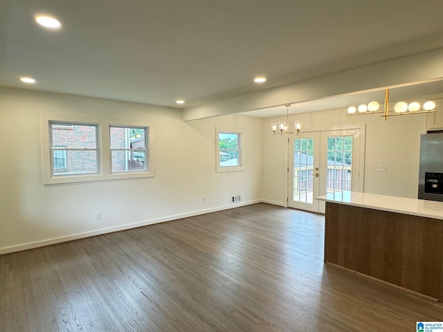 unfurnished living room featuring dark wood-style flooring, visible vents, baseboards, a notable chandelier, and recessed lighting