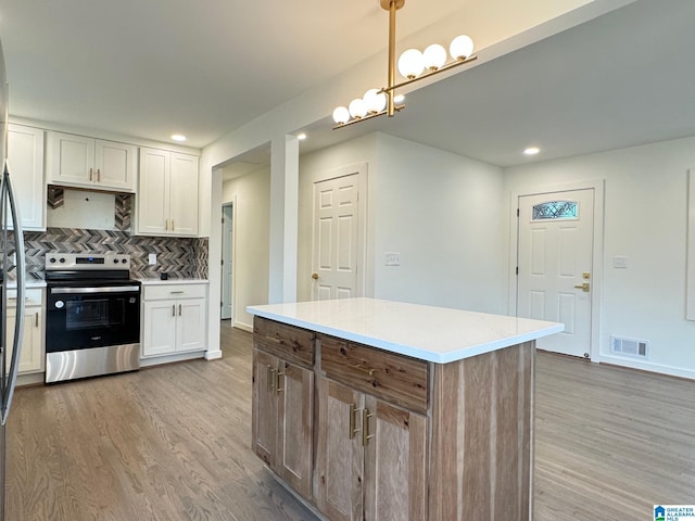 kitchen with stainless steel electric range, visible vents, decorative backsplash, and light wood-style flooring