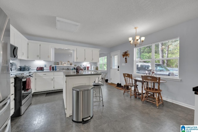 135 Hayden Springs Rd, Hayden, AL 35079 - kitchen featuring a textured ceiling, white cabinets, appliances with stainless steel finishes, a center island, and a notable chandelier