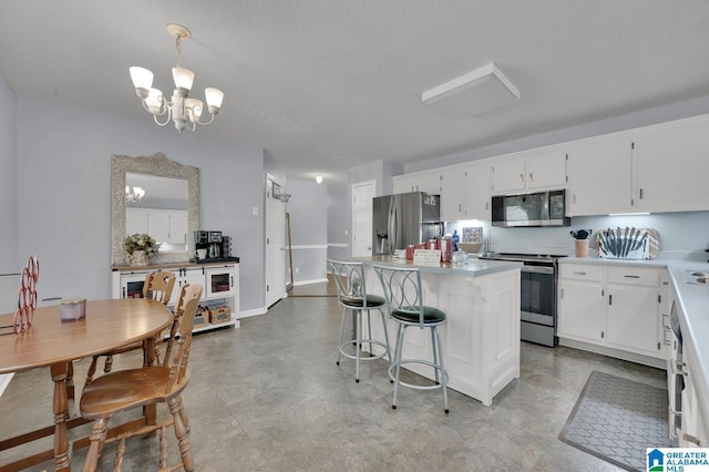135 Hayden Springs Rd, Hayden, AL 35079 - kitchen with an inviting chandelier, appliances with stainless steel finishes, light countertops, white cabinetry, and a center island