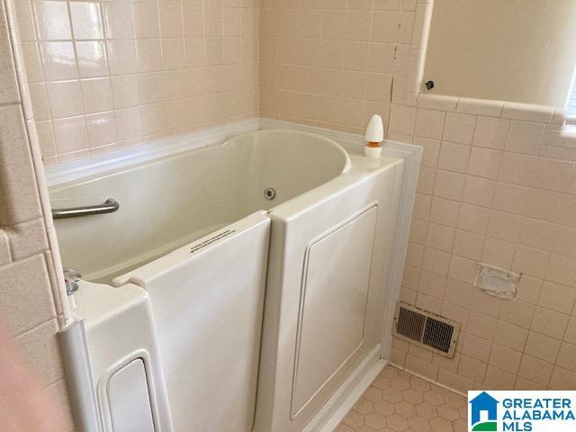 4905 Spunky Hollow Rd, Remlap, AL 35133 - bathroom with tile walls, visible vents, tile patterned flooring, and a whirlpool tub
