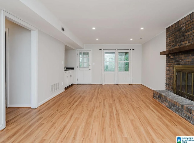unfurnished living room with baseboards, visible vents, a fireplace, and light wood finished floors