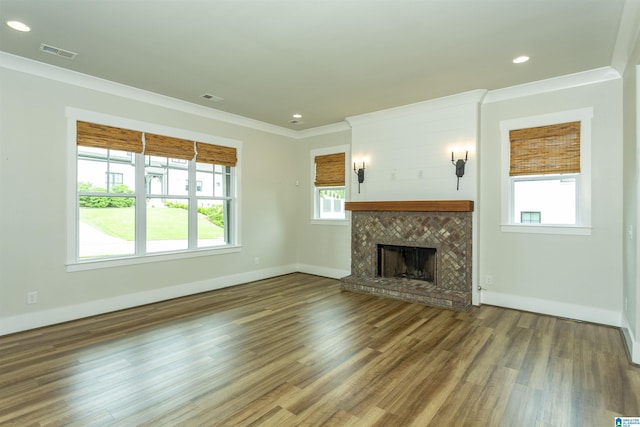 unfurnished living room featuring visible vents, crown molding, wood finished floors, baseboards, and a fireplace with raised hearth