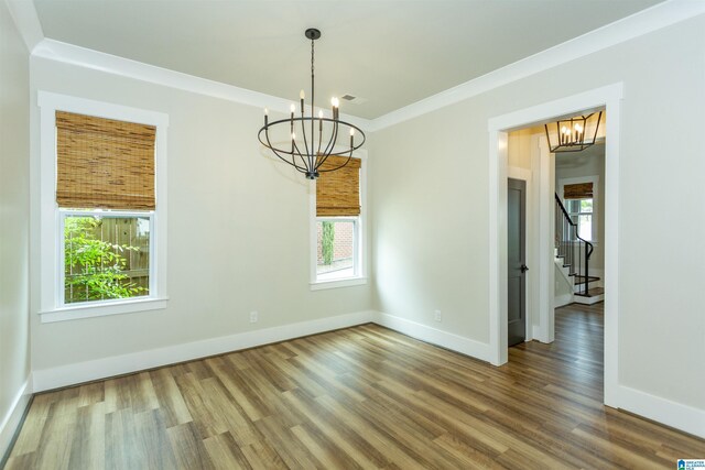 unfurnished dining area featuring stairway, baseboards, wood finished floors, and a notable chandelier