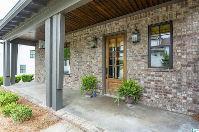 property entrance featuring covered porch and brick siding
