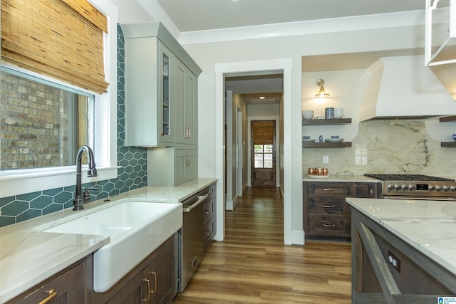 kitchen featuring backsplash, appliances with stainless steel finishes, a sink, and wood finished floors
