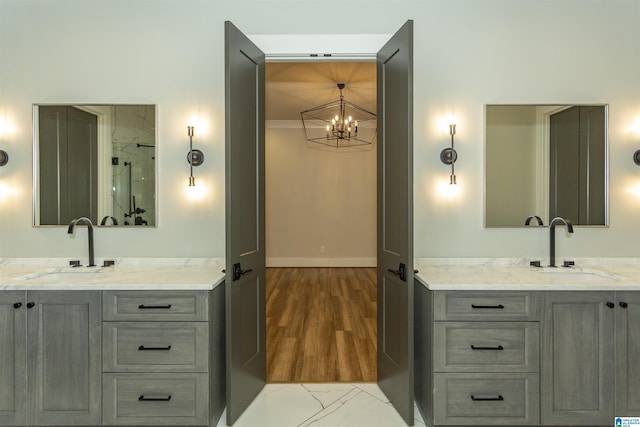 bathroom featuring a sink, a chandelier, and two vanities
