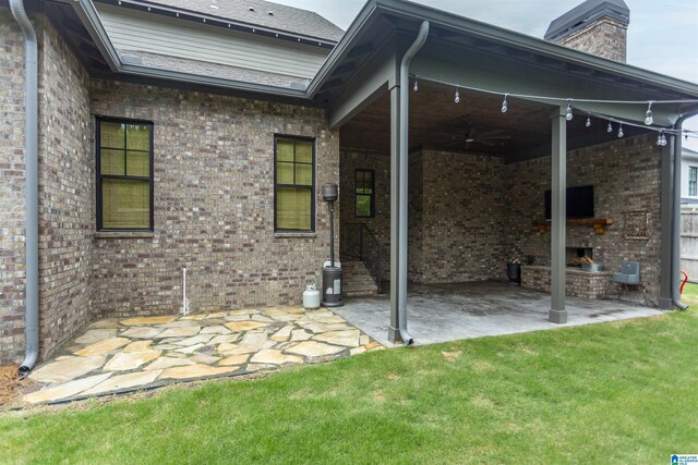 back of property with brick siding, a patio area, and a fireplace