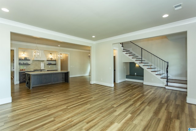 unfurnished living room with stairs, recessed lighting, a notable chandelier, and wood finished floors