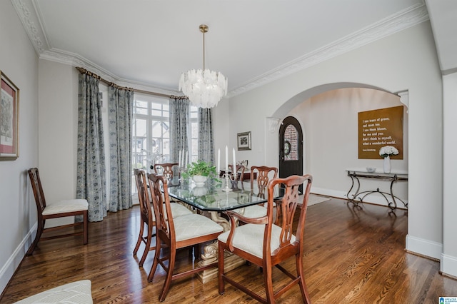 dining room with crown molding, arched walkways, an inviting chandelier, and wood finished floors