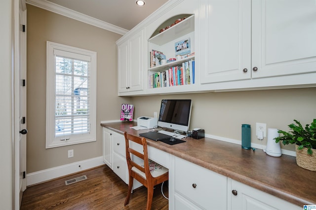 office with dark wood-style flooring, built in study area, baseboards, visible vents, and ornamental molding