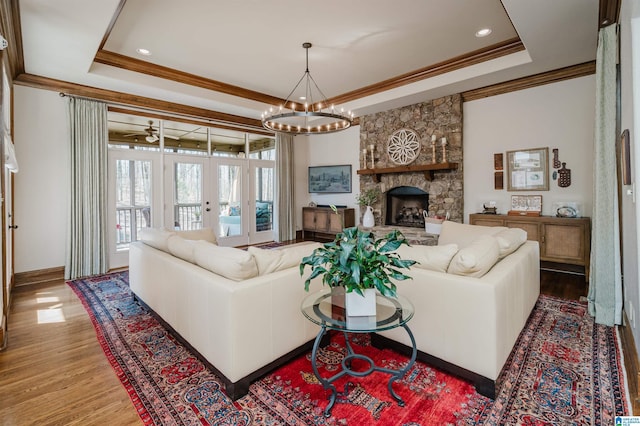 living room with a tray ceiling, ornamental molding, and wood finished floors