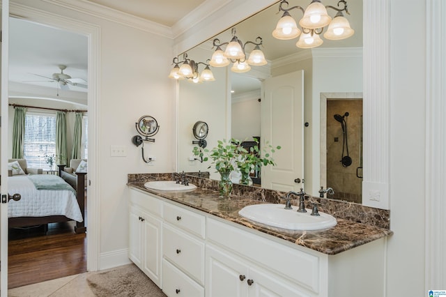 ensuite bathroom featuring a sink, crown molding, and double vanity