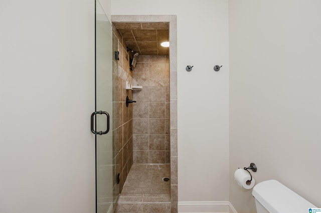 bathroom with toilet, baseboards, and a shower stall