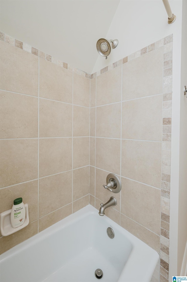 bathroom featuring washtub / shower combination and lofted ceiling