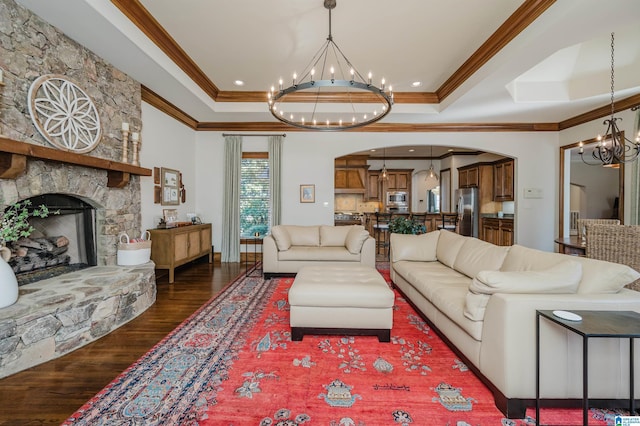 living area featuring an inviting chandelier, arched walkways, ornamental molding, and a tray ceiling